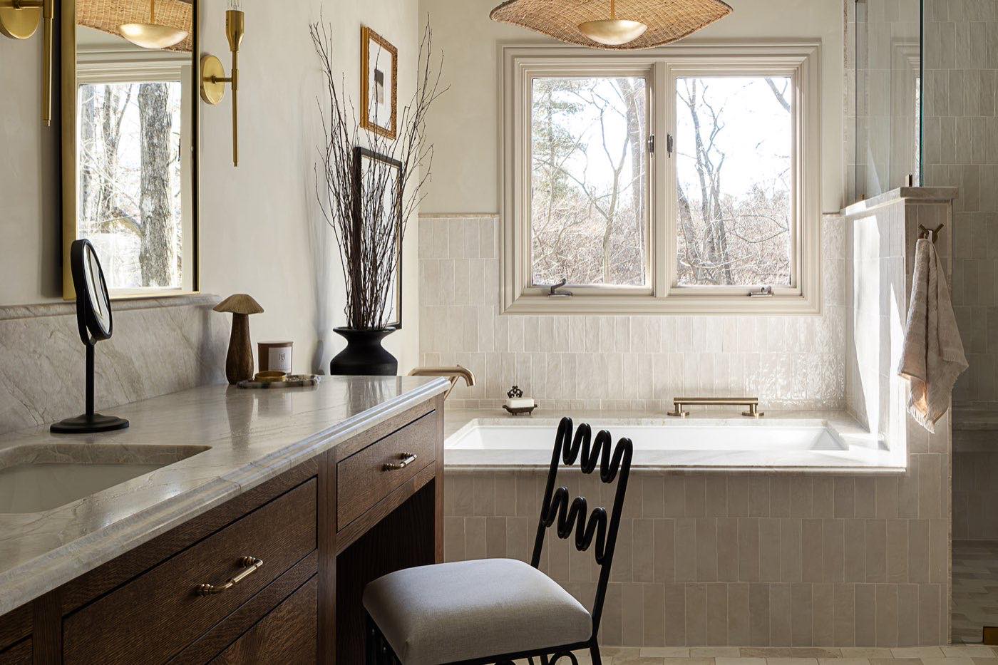 Primary bathroom with honed stone vanity, aged brass sconces and dark oak cabinetry